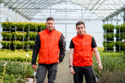 Deux hommes avec un veste orange debout dans une serre